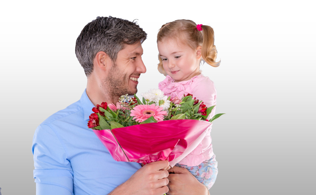 Vater mit kleiner Tochter, die einen Blumenstrauß hält