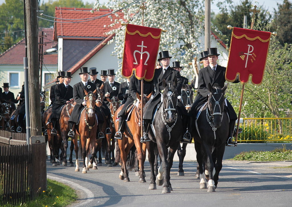 Reiter in dunklen Uniformen mit roten Fahnen auf einer Straße